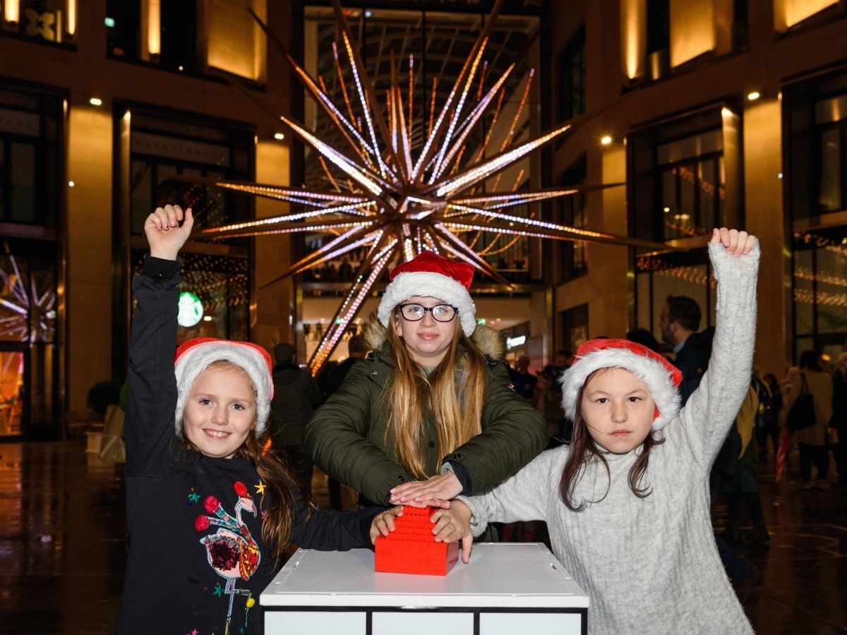 three children pressing button to switch on christmas lights