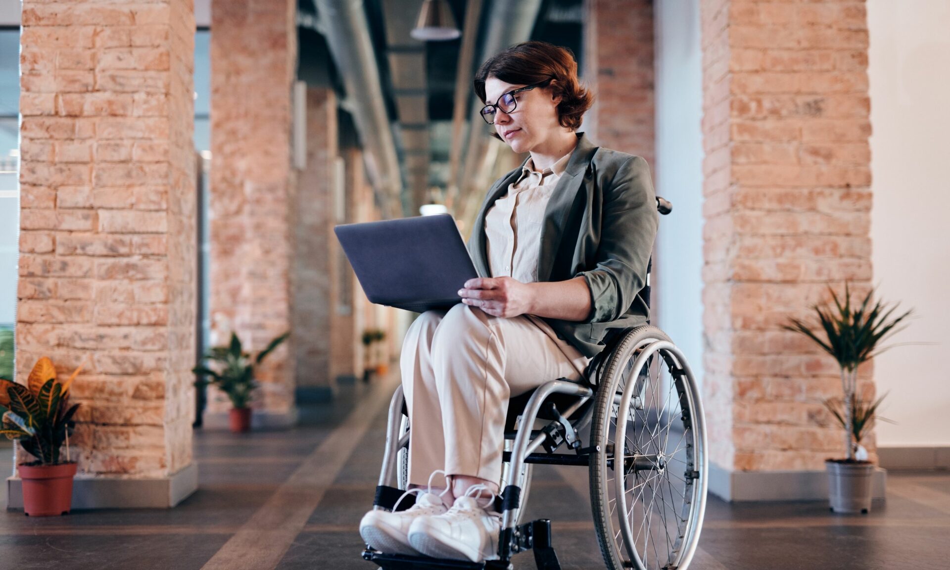 Woman in wheelchair using laptop at work