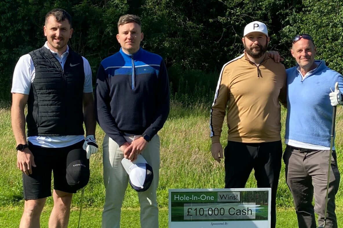 four happy golfers in edinburgh standing in front of a sign reading hole in one