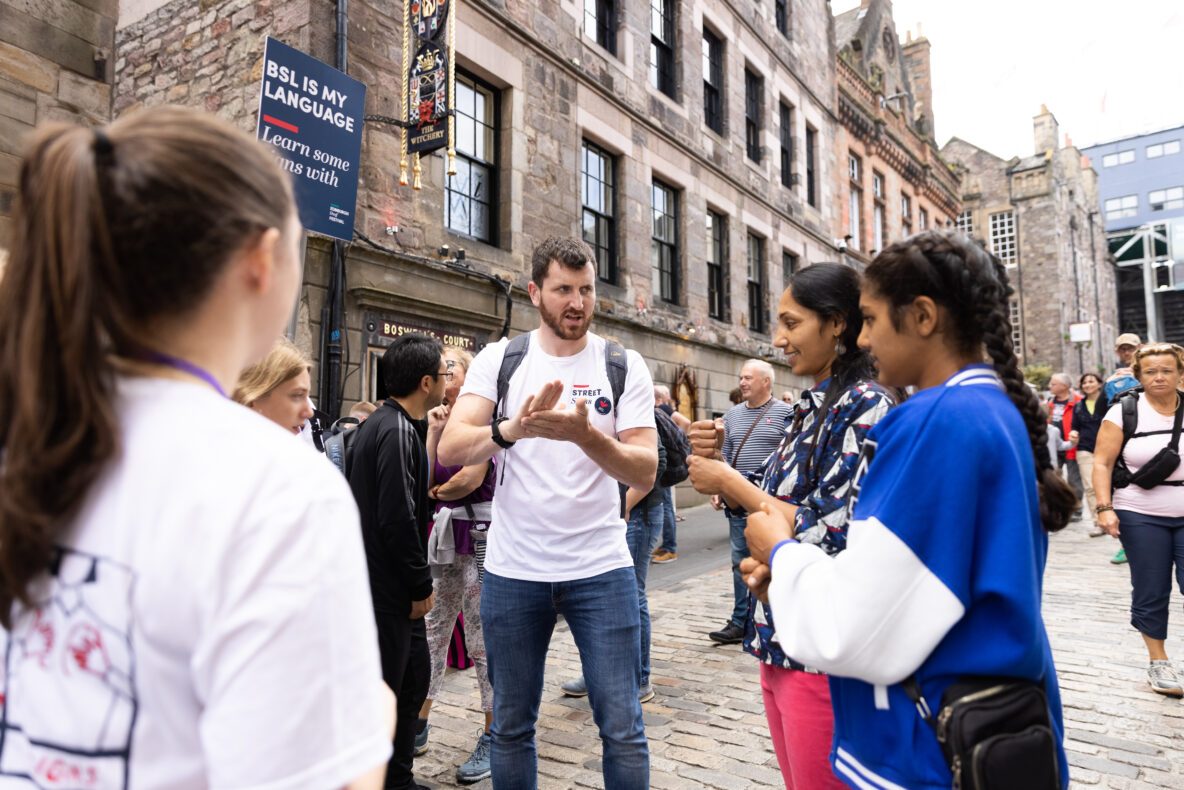 DEaf Action team member teaching people BSL British Sign Language on Edinburgh's Royal Mile.