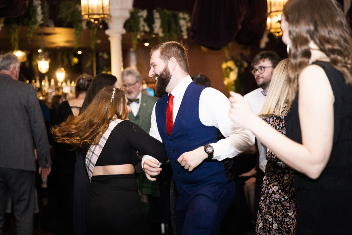 People dressed smartly and in tartan dancing at a ceilidh